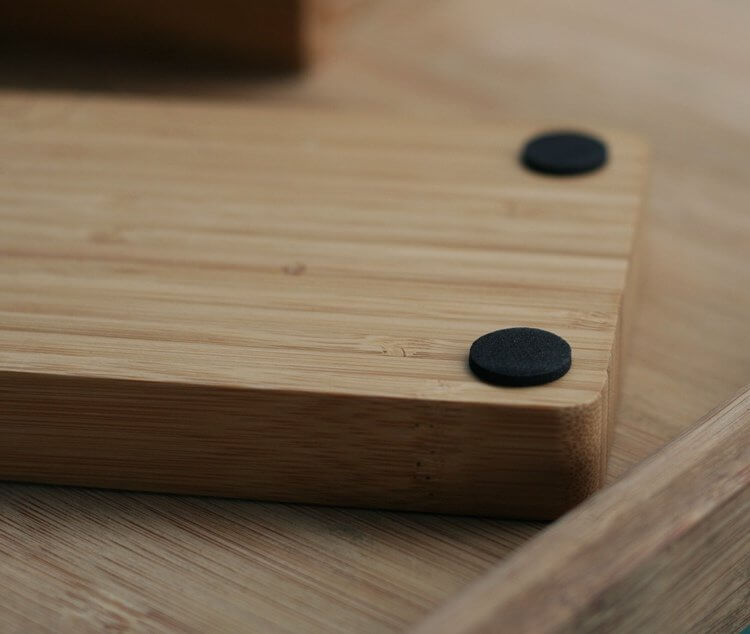 Close-up of a bamboo desktop organizer showcasing its natural finish and black rubber feet for stability.