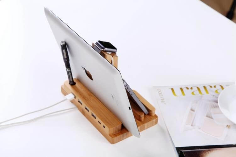 Bamboo docking station with 4 USB ports, holding an iPad and accessories on a stylish desk.