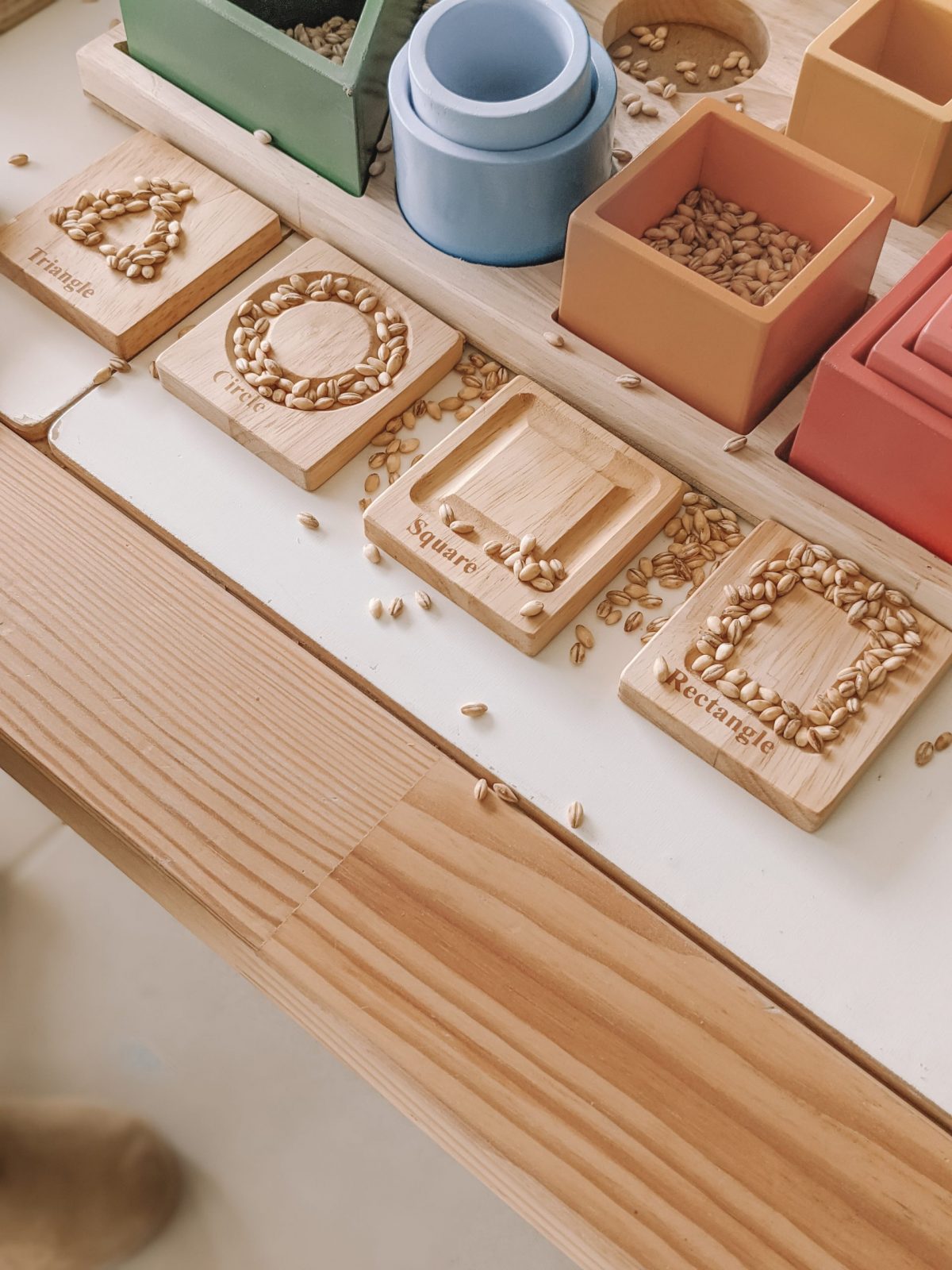Colorful wooden sorting board with shapes and seeds, promoting fine motor skills for toddlers.
