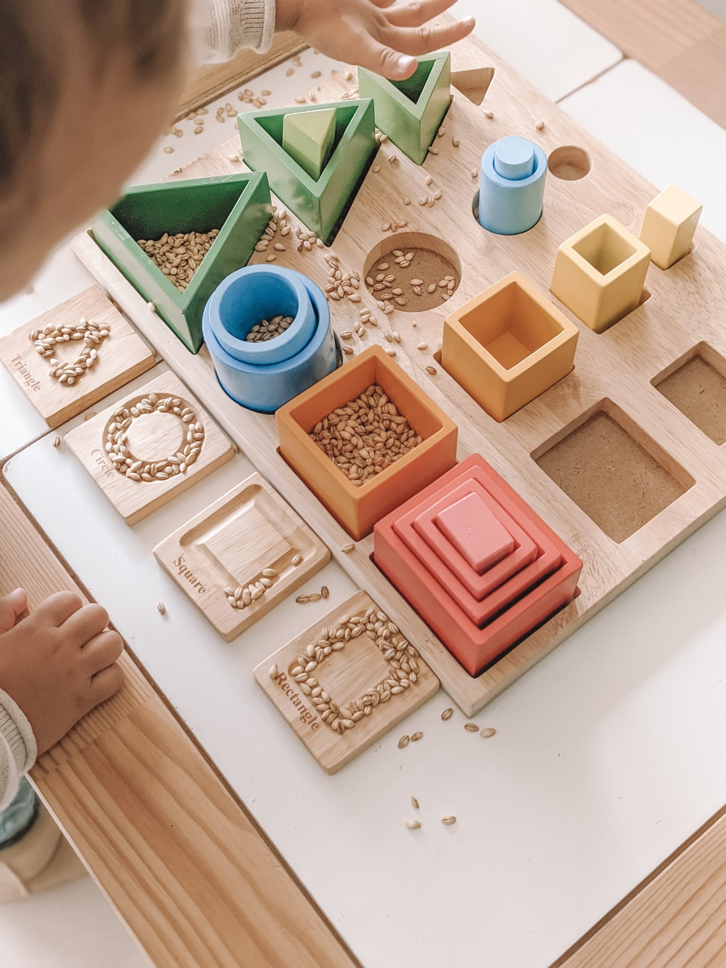 Child exploring a 3D sorting and nesting board with colorful shapes and textures for fine motor skill development.