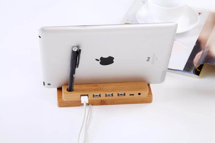 Bamboo docking station with 4 USB ports, holding an iPad and pen, eco-friendly charging solution.