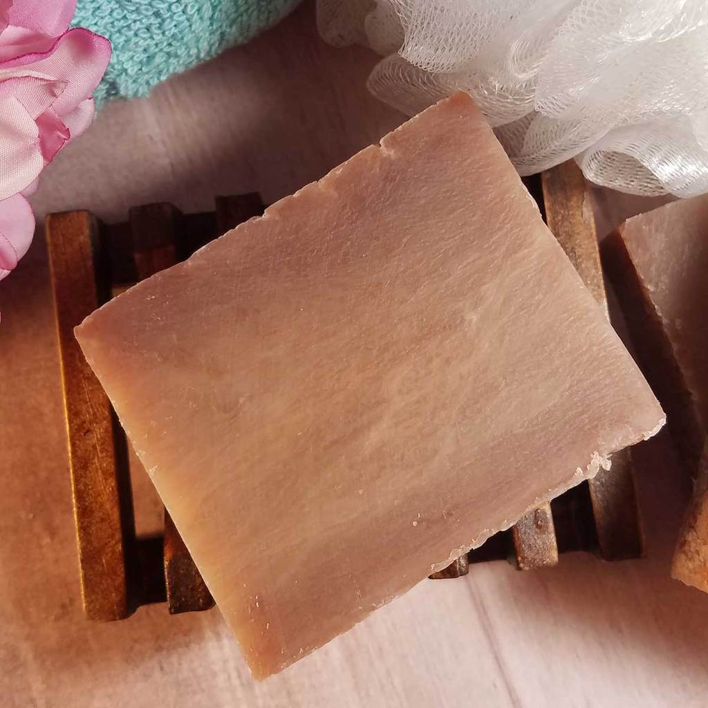 All Natural Coconut Handmade Soap bar on a wooden soap dish, showcasing its creamy texture and light color.