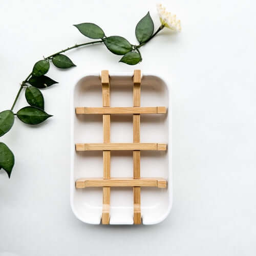 Biodegradable bamboo and cornstarch soap dish with removable grid for drainage against a light background.
