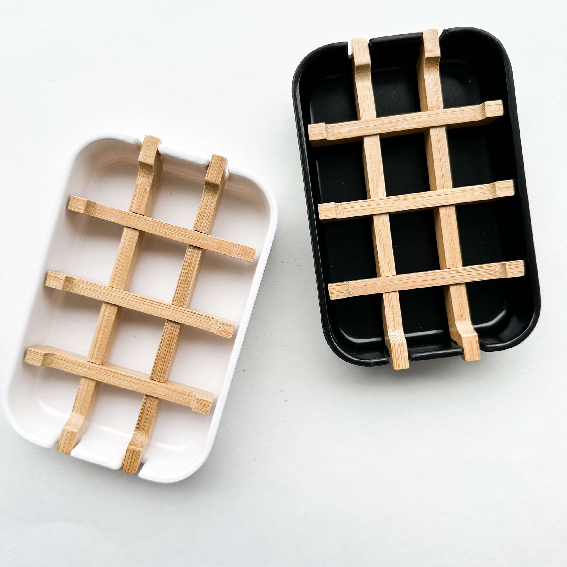 Biodegradable bamboo and cornstarch soap dish in black and white with removable bamboo grid for drainage.