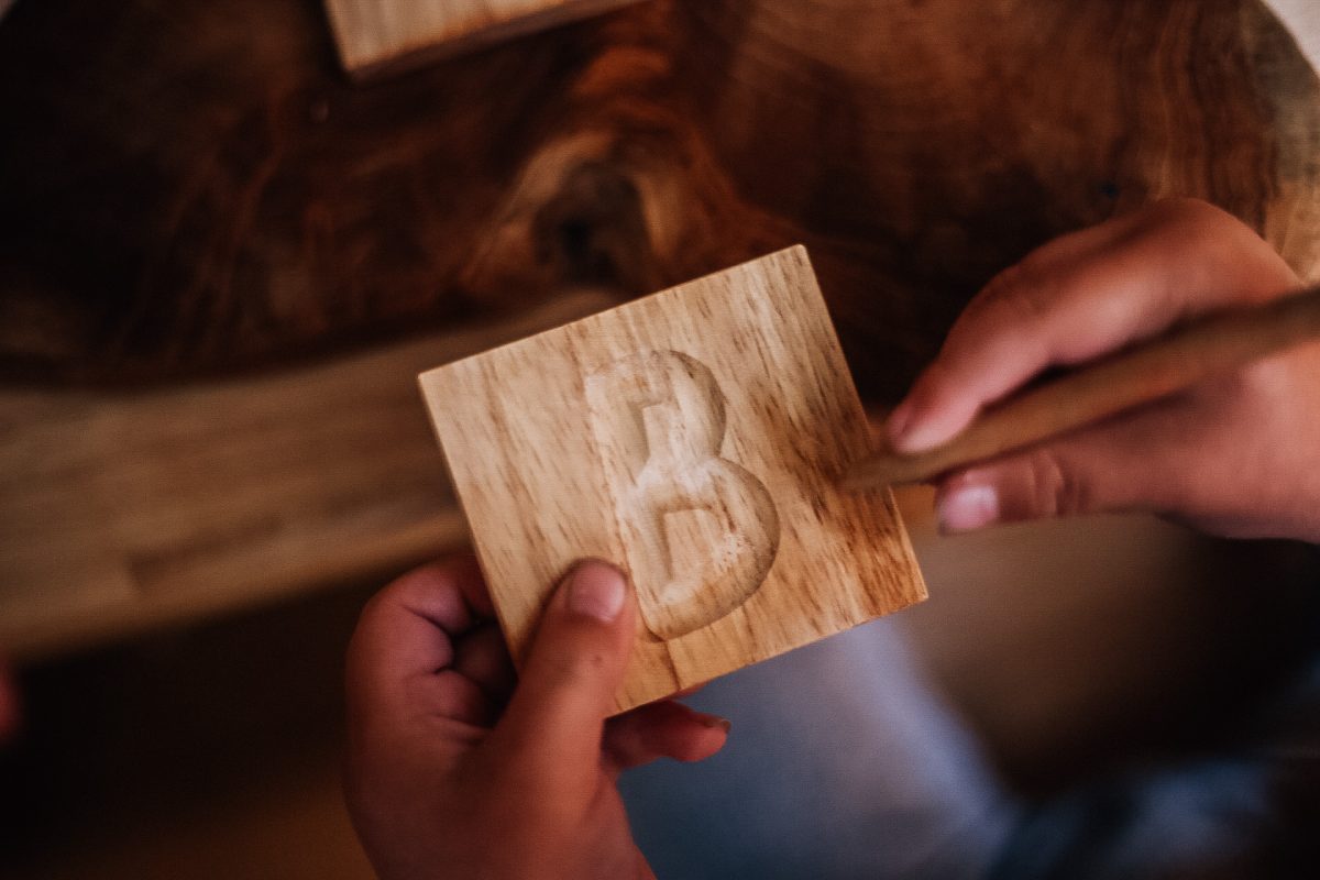 Child tracing the letter 'B' on a wooden Capital Letter Tray, promoting literacy and creativity.