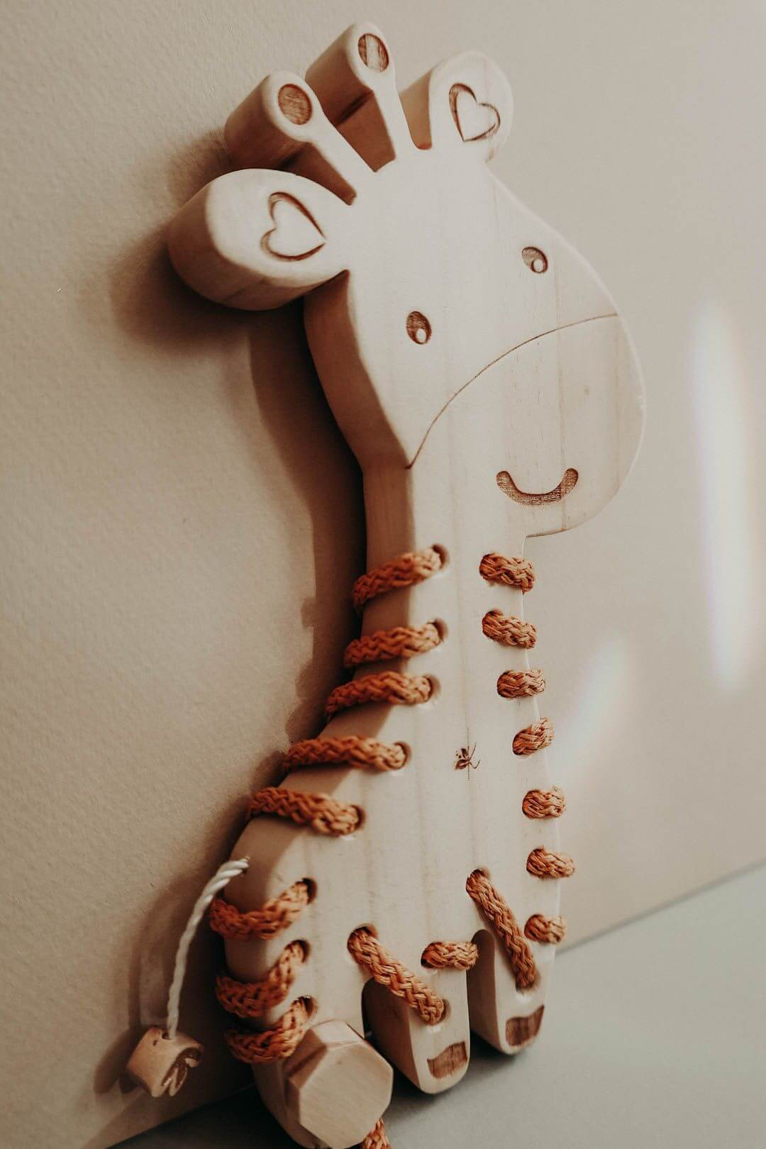 Handmade wooden giraffe lacing toy for kids, promotes fine motor skills and hand-eye coordination.