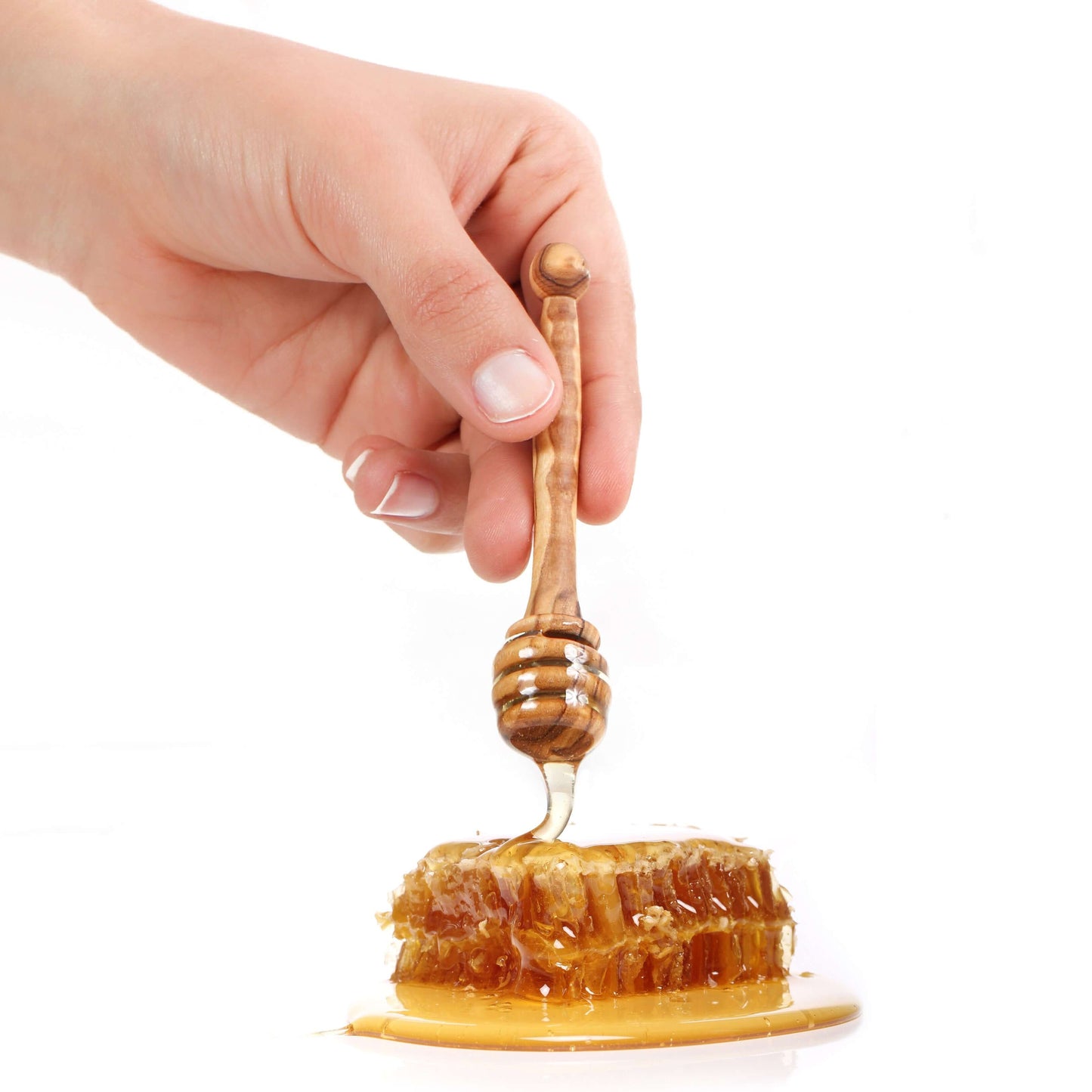 Hand holding an olive wood honey dipper drizzling honey over a honeycomb, showcasing eco-friendly kitchenware.