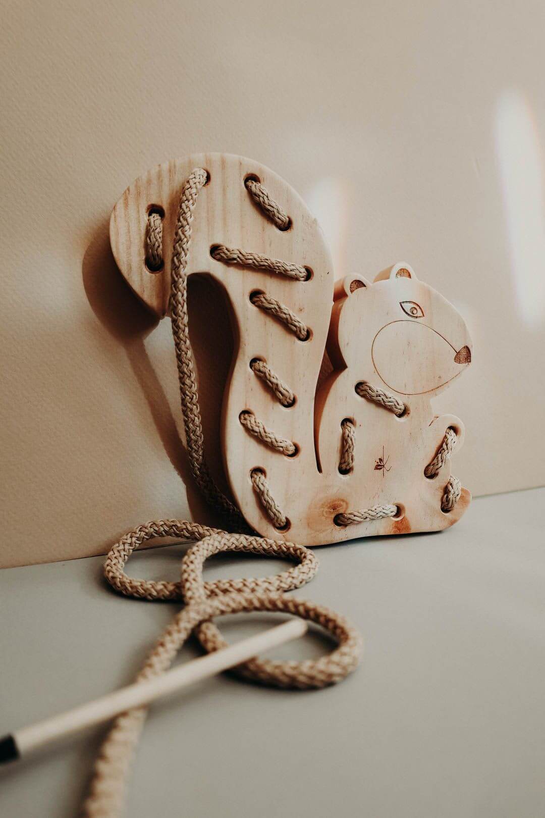 Wooden squirrel lacing toy, handmade from pinewood with cotton cord for Montessori pre-writing skills.