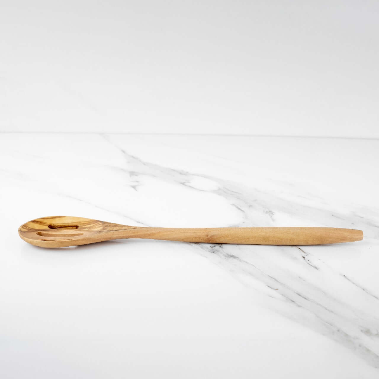 Handmade 35cm olive wood slotted spoon on a marble surface, durable and elegant kitchen utensil for cooking.