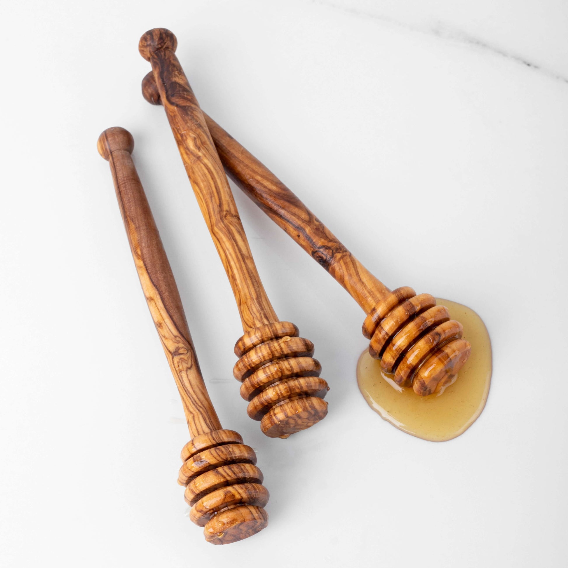 Set of handmade olive wood honey dipper drizzlers, perfect for capturing honey with style.