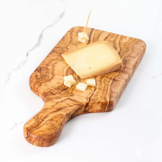 Handmade olive wood cutting board with cheese and cubes, showcasing durability and rustic charm for meal prep.