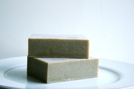 Dead Sea mud soap bar stacked on a white plate, showcasing its natural color and texture for a mineral-rich skincare experience.
