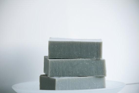 Stack of handmade Dead Sea mud soap bars on a white plate, showcasing their mineral-rich skincare benefits.