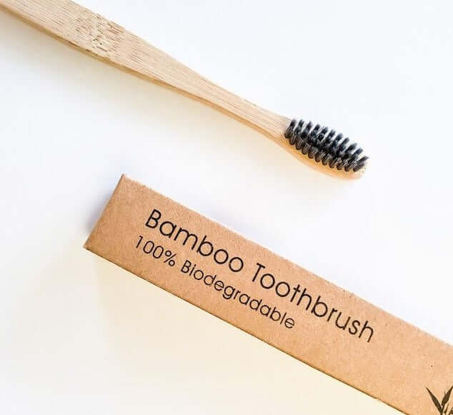 Eco-friendly bamboo toothbrush with activated charcoal bristles and biodegradable packaging.