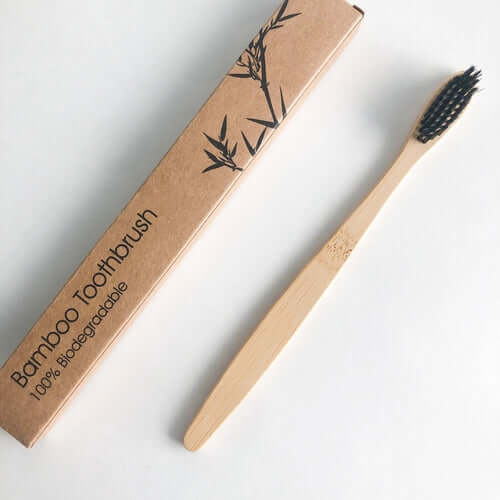 Eco-friendly bamboo toothbrush with activated charcoal bristles, packaged in a biodegradable box.