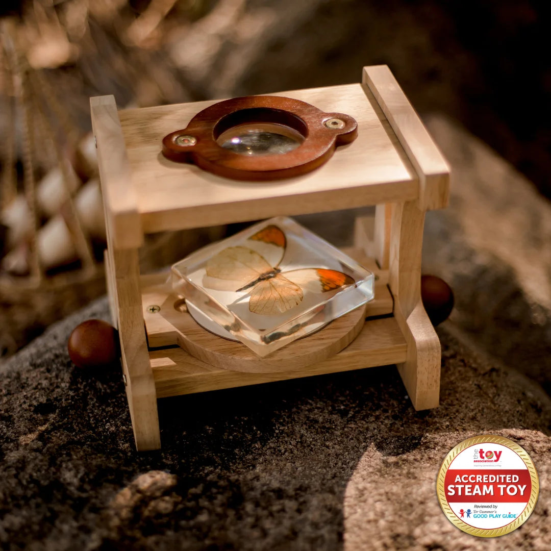 Wooden microscope on a natural surface, featuring a butterfly specimen, promoting educational exploration for kids.