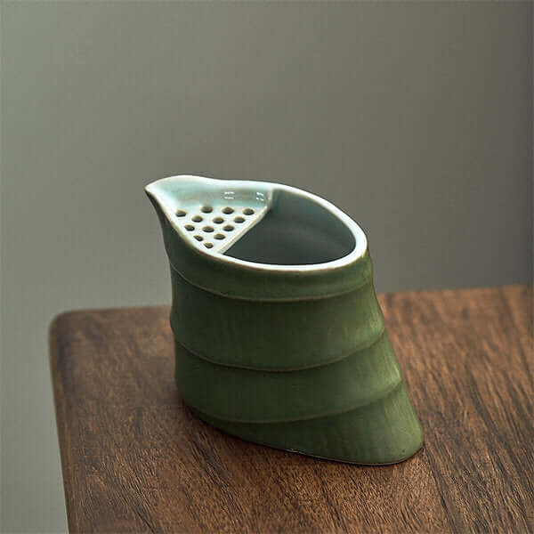 Elegant green bamboo ceramic cup with a unique design, perfect for tea or as a decorative utensil on a wooden surface.