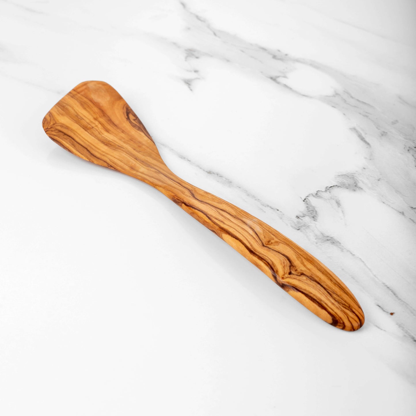 Handmade olive wood corner spatula on a marble countertop, perfect for precise cooking in corners.