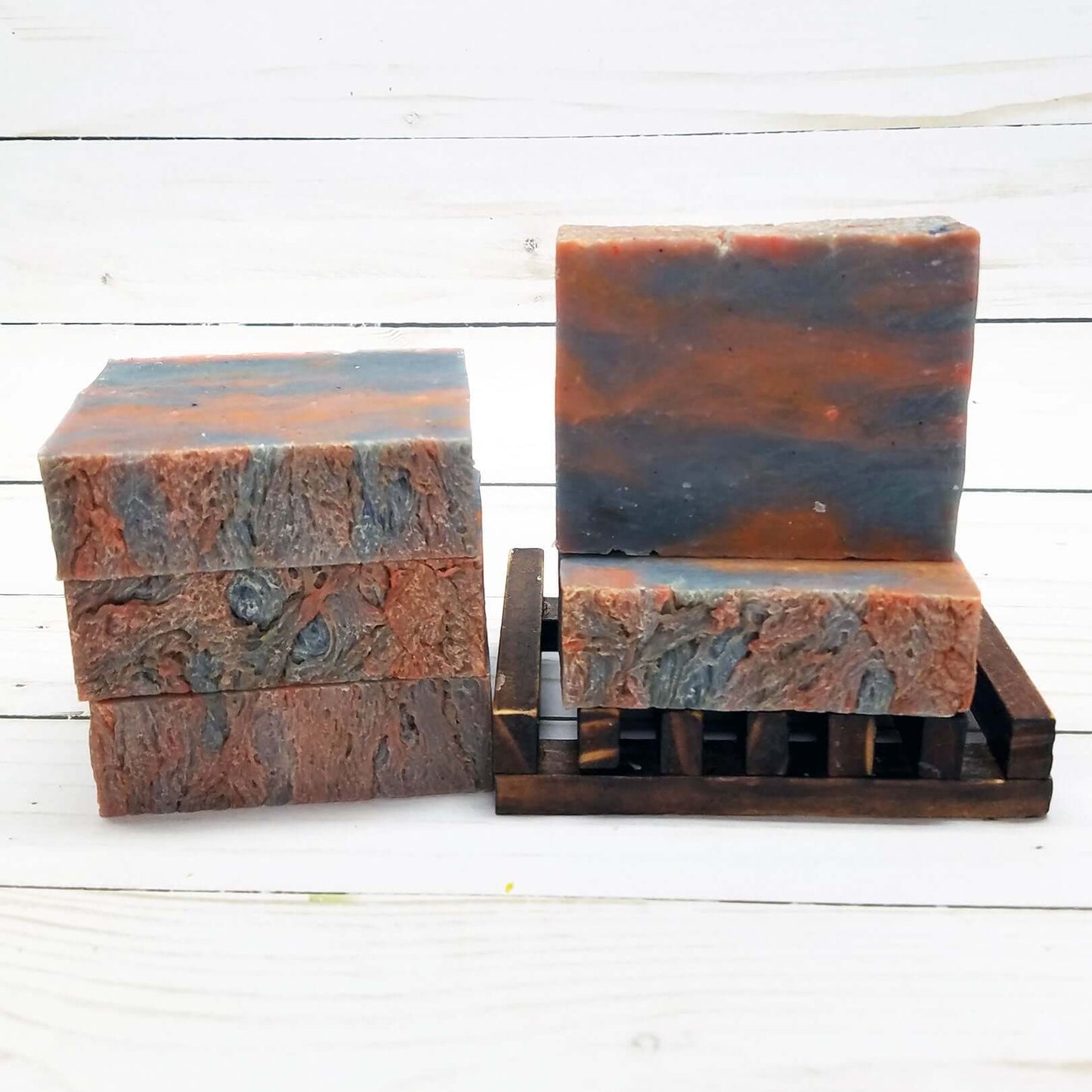 Lakeside Fire handmade soap bars in earthy hues on a wooden soap dish, evoking a serene lakeside experience.