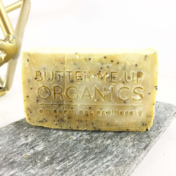 Natural lemon poppyseed soap bar with exfoliating poppyseeds on a stone surface.