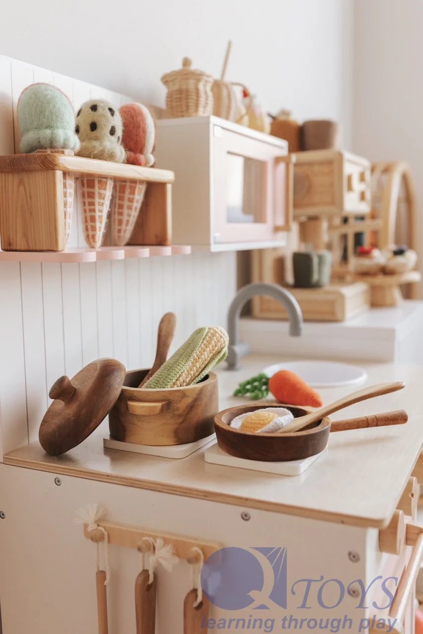 Colorful wooden kitchen set with pots, utensils, and toy vegetables for imaginative play.