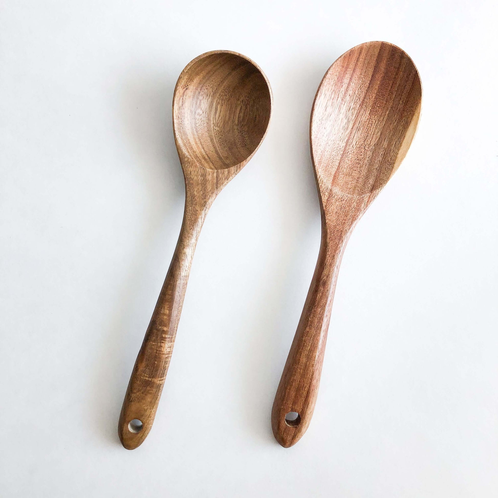 Natural acacia wood kitchen utensils set, featuring two handcrafted wooden serving spoons for durable cooking.