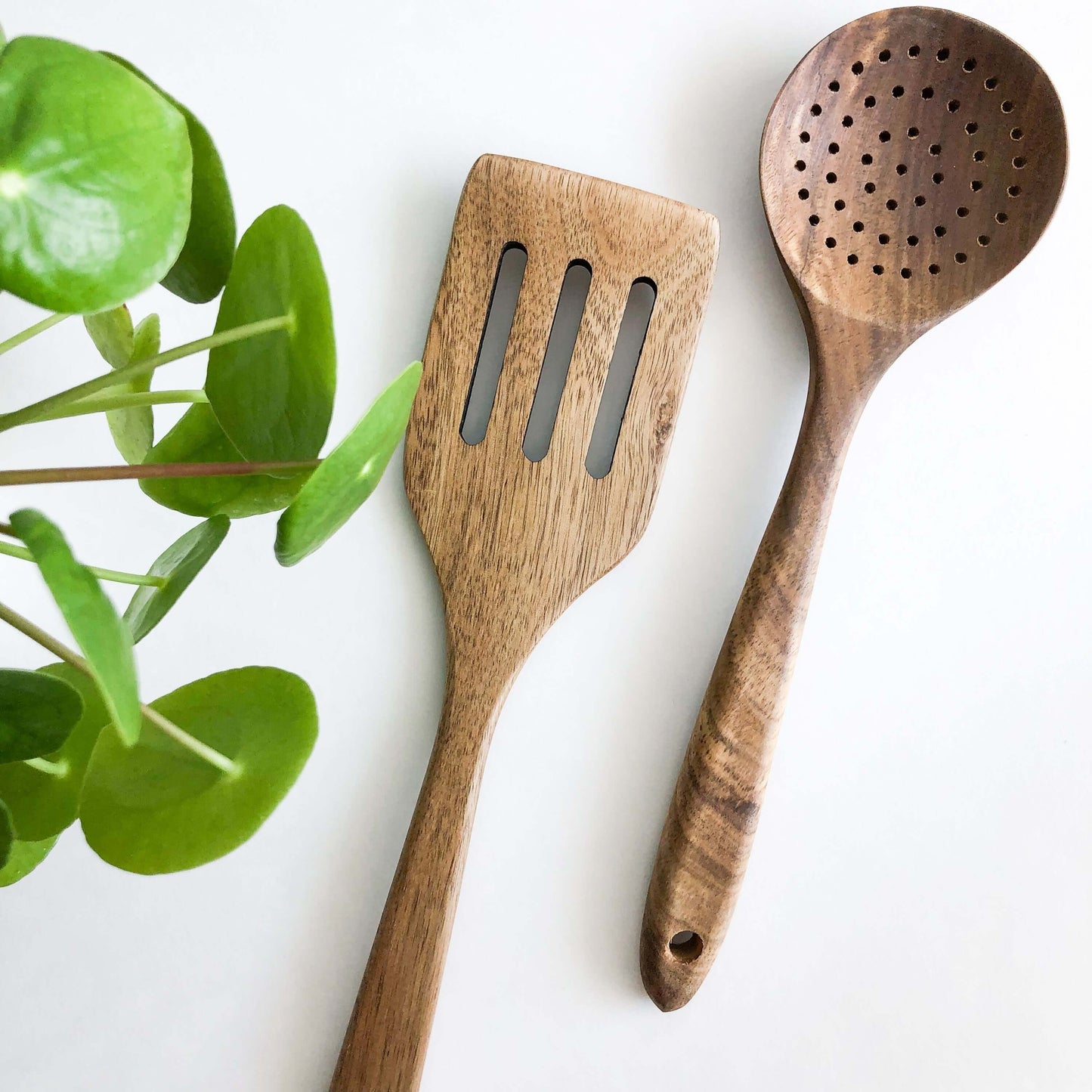 Natural acacia wood kitchen utensils including slotted spatula and skimmer, designed for non-stick cookware.