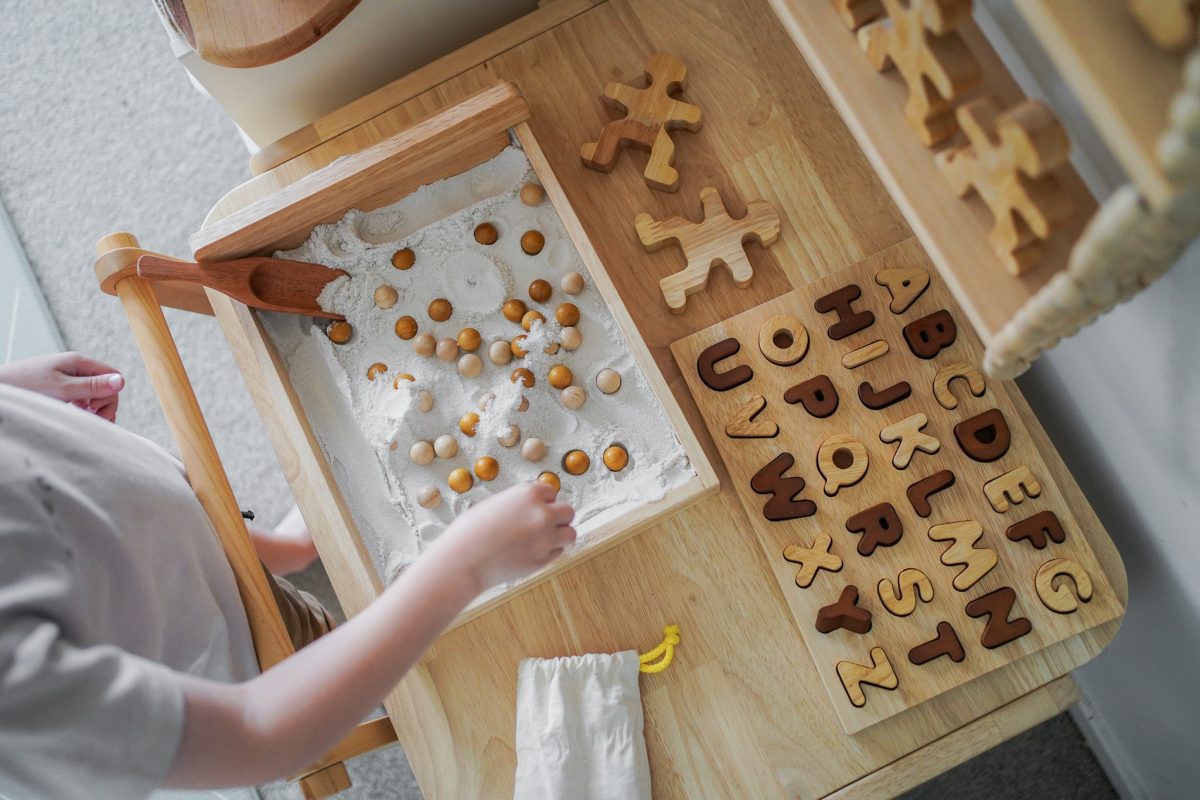 Child interacting with Natural Capital Letter Puzzle, eco-friendly learning toy, for letter recognition.