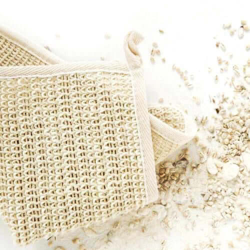 Natural sisal washcloth for gentle exfoliation, surrounded by organic grains on a white background.