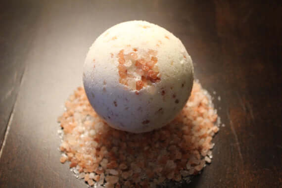 Organic bath fizzie resting on pink Himalayan salt, ideal for detoxifying tired skin and enhancing relaxation.