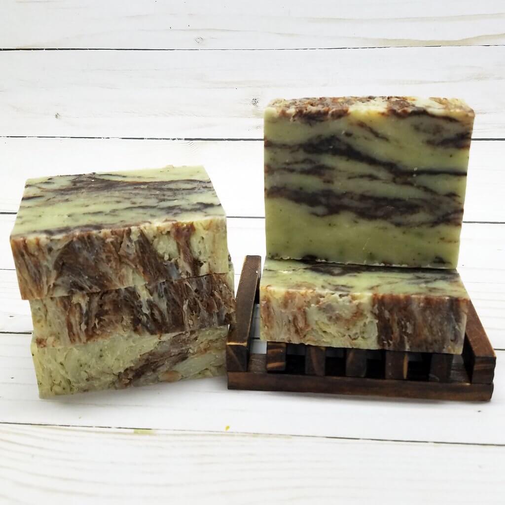 Organic mint chocolate soap bars with rich brown swirls on a wooden soap dish.
