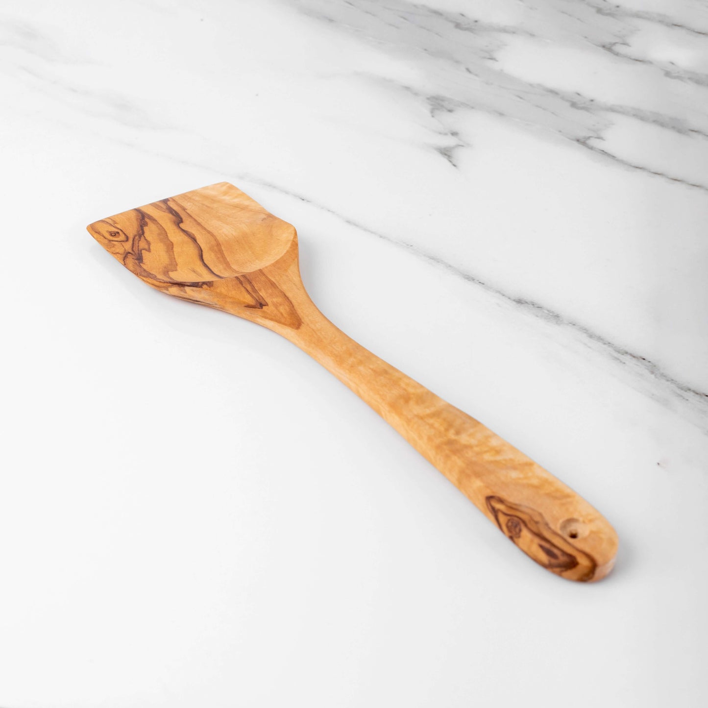 Handmade 11.8" olive wood spatula on marble surface, featuring a smooth handle and unique grain.