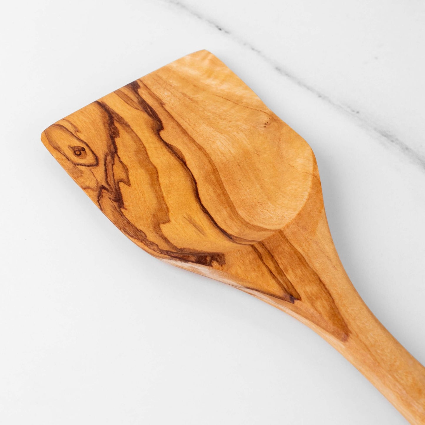 Handmade olive wood spatula with a smooth flat rectangular head for easy flipping and stirring.
