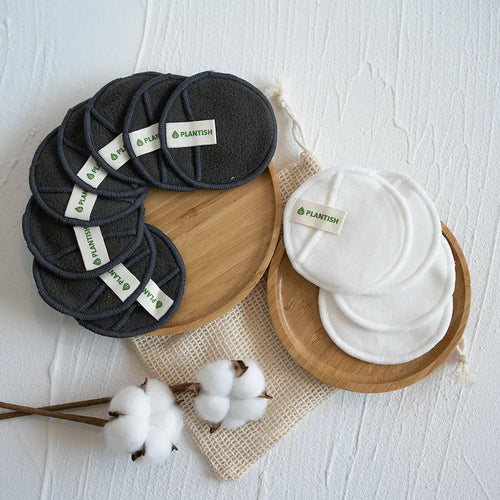 Reusable cotton makeup removal rounds in charcoal and white on bamboo plates, eco-friendly skincare essentials.