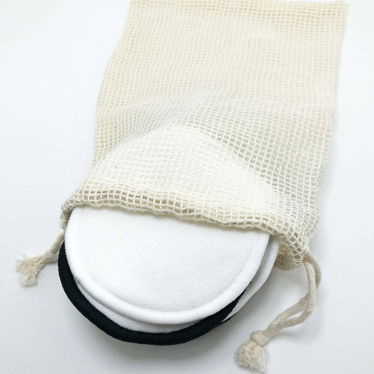 Organic bamboo cotton facial pads stored in a reusable mesh bag for eco-friendly skincare.