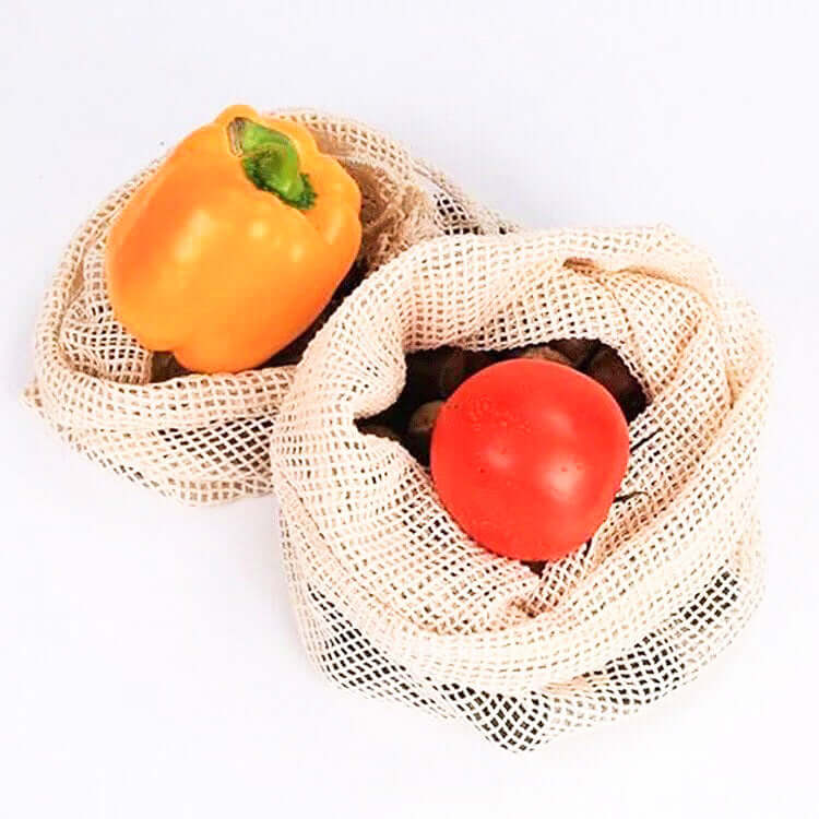 Reusable organic cotton mesh produce bag with fresh bell pepper and tomato, promoting zero waste and plastic-free living.