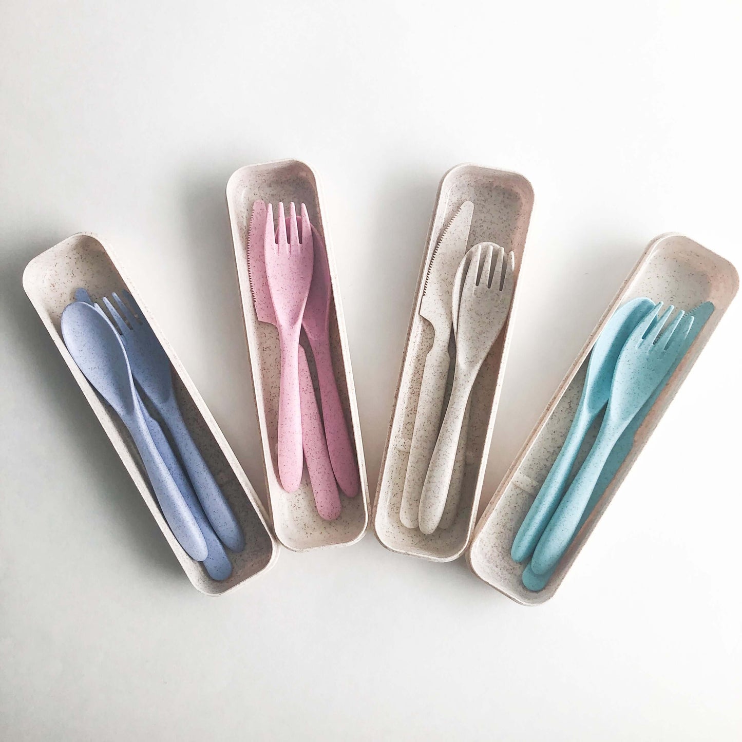 Colorful reusable wheat straw cutlery set in eco-friendly storage boxes, ideal for reducing single-use plastic.
