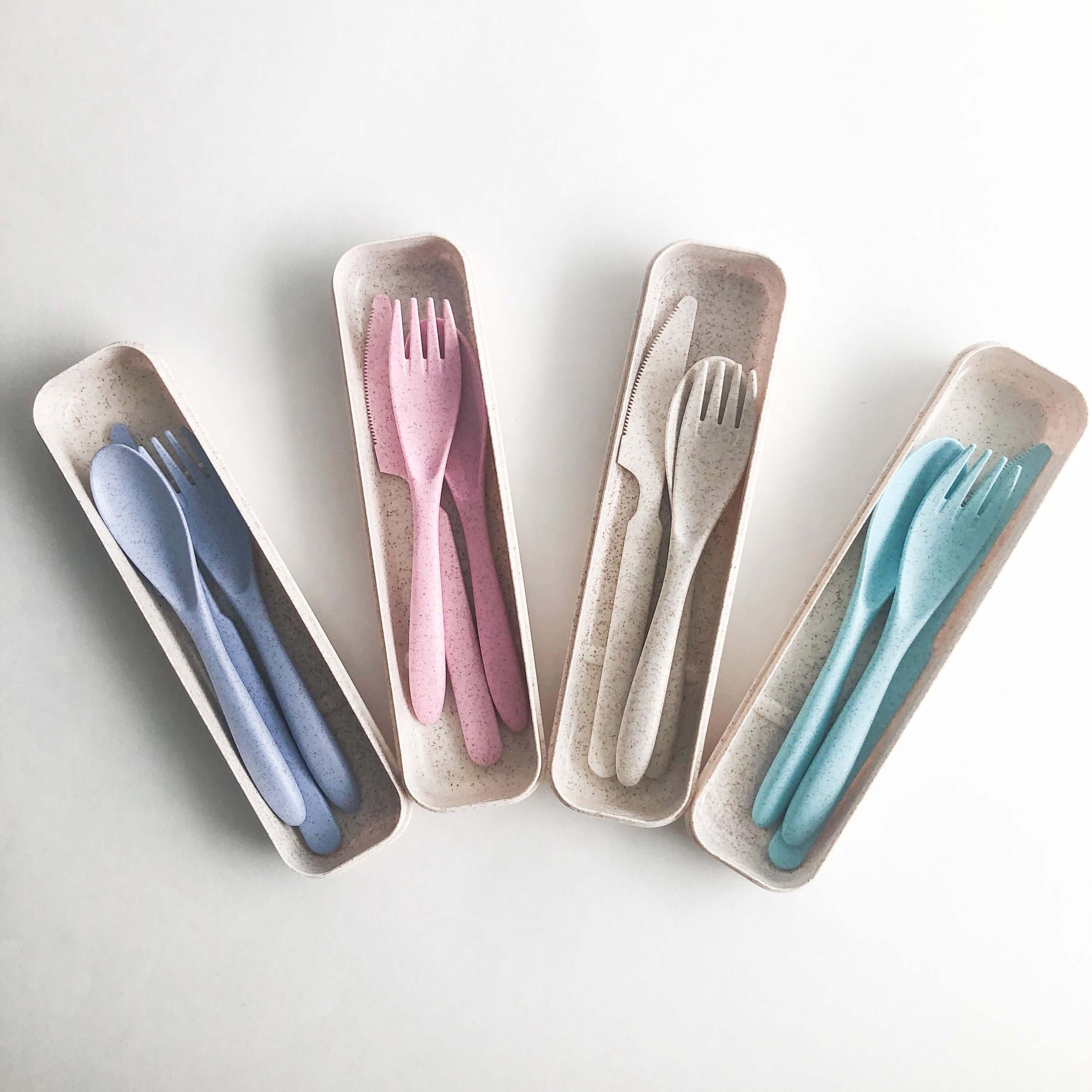 Colorful reusable wheat straw cutlery set in eco-friendly storage boxes, ideal for reducing single-use plastic.