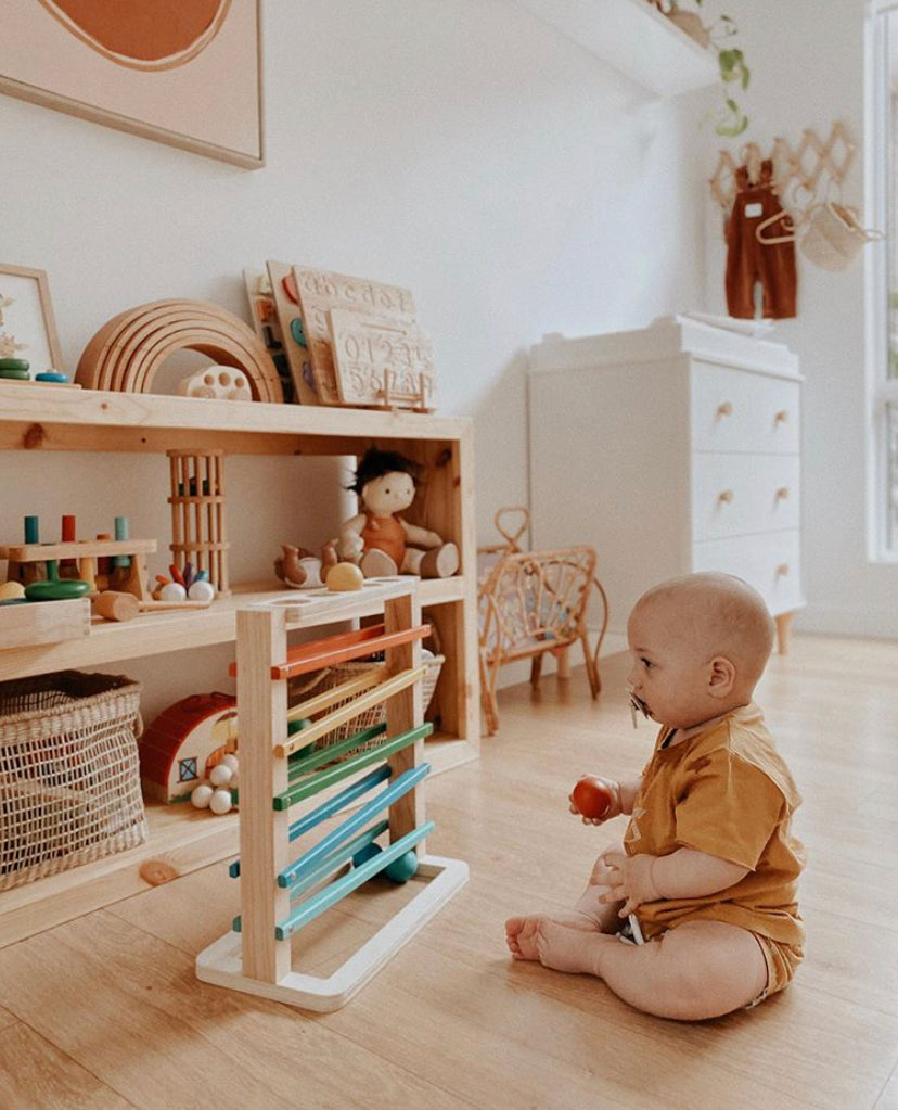Toddler playing with the Track a Ball Rack wooden toy, promoting hand-eye coordination and visual tracking.