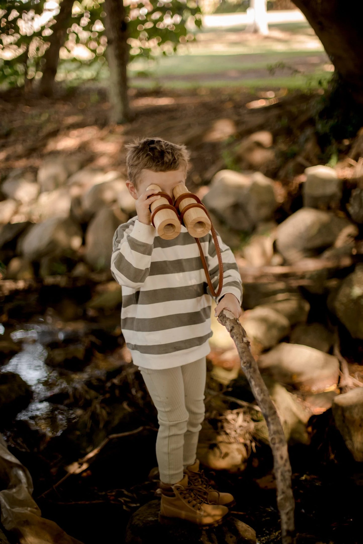 Child exploring outdoors with wooden binoculars, fostering imagination and adventure.