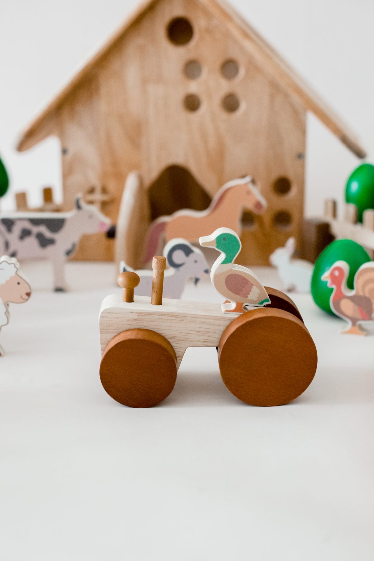 Wooden tractor toy surrounded by colorful farm animals, perfect for imaginative play and toddler development.