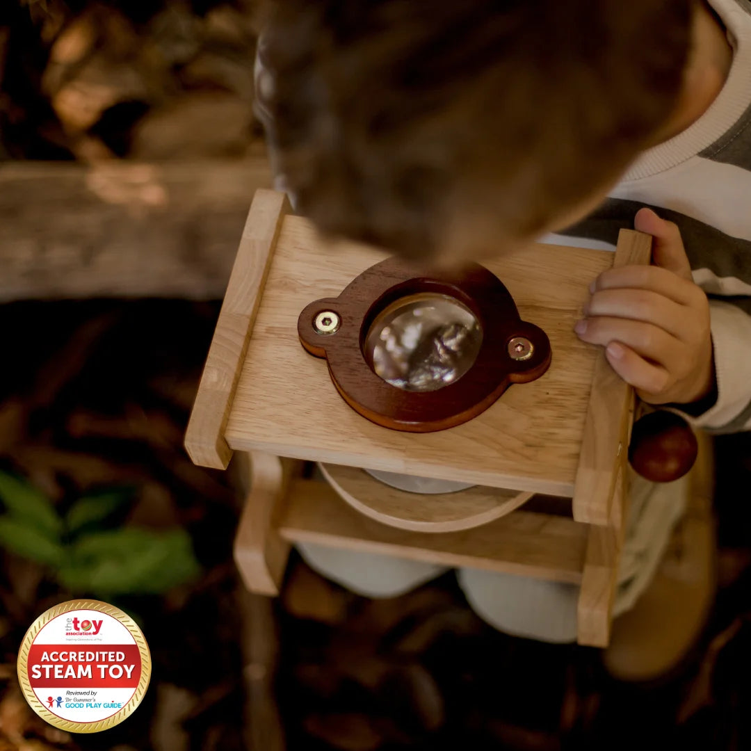 Child exploring nature with a wooden microscope, an eco-friendly educational toy that encourages scientific curiosity.