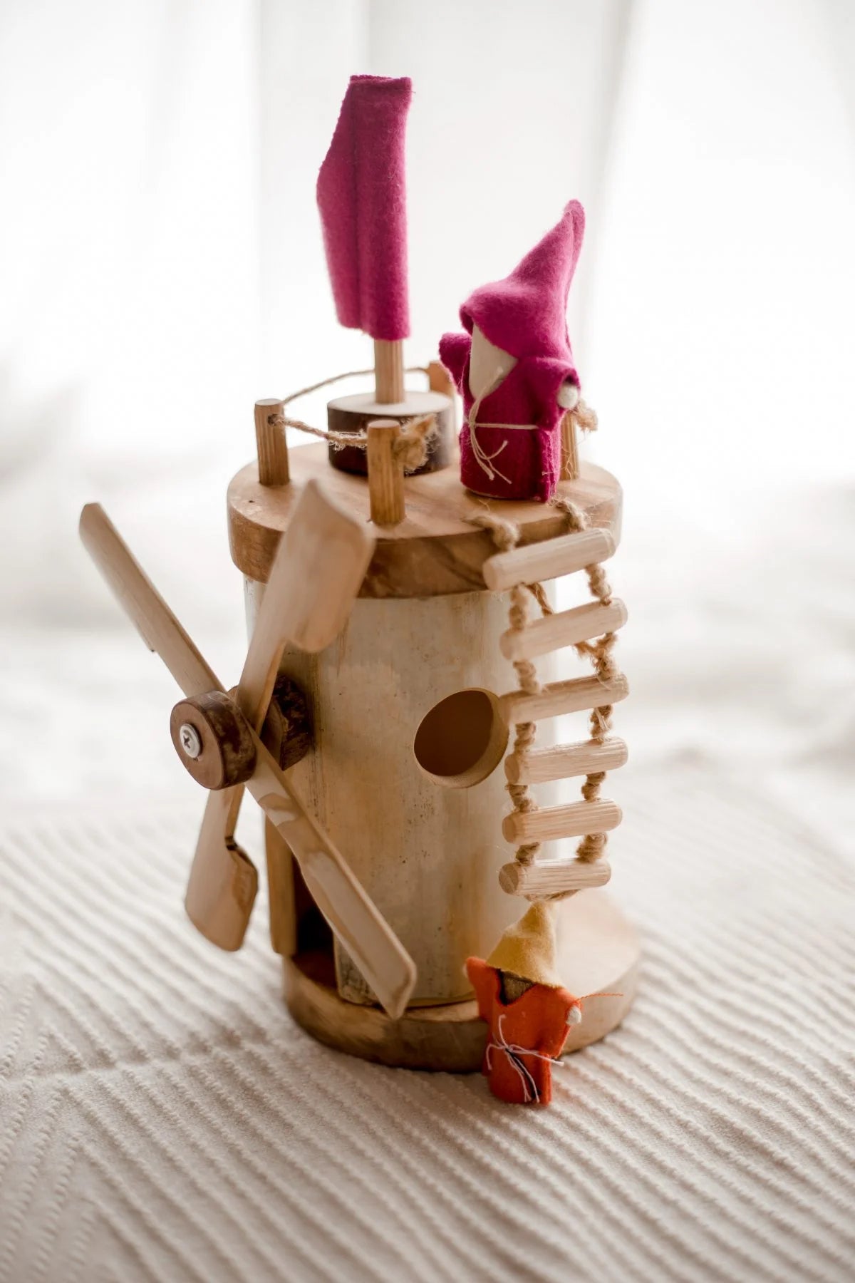 Wooden windmill toy with spinning blades, colorful figures, and ladder for imaginative play and storytelling.