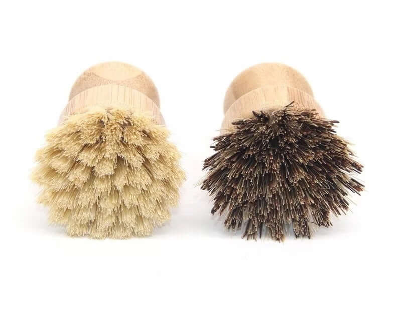 Two bamboo pot scrubbers: one with soft natural bristles, the other with sturdy dark bristles for versatile cleaning.