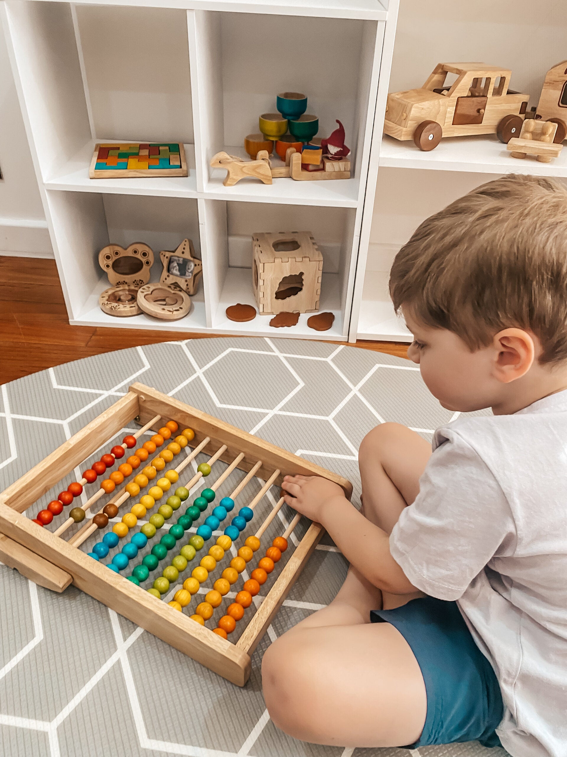 Toddler using a wooden bead counting abacus to learn numbers and improve fine motor skills.