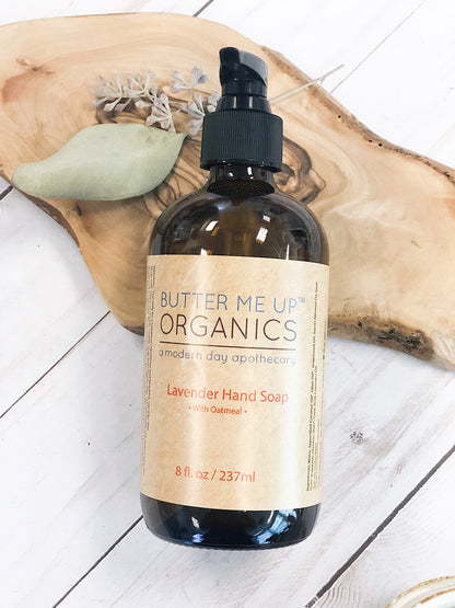 Butter Me Up Organics Lavender Hand Soap with Oatmeal in an amber bottle, 8 oz, resting on a wooden surface.