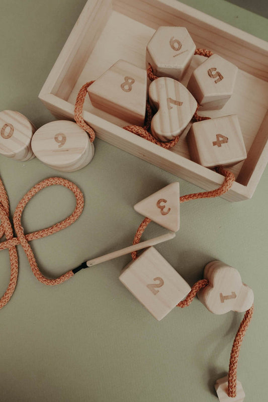 Wooden lacing toy featuring numbers and geometric shapes, enhancing fine motor skills and hand-eye coordination for kids.