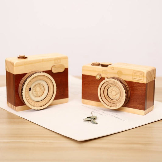 Wood camera music boxes on a table, showcasing fine craftsmanship and playful design.