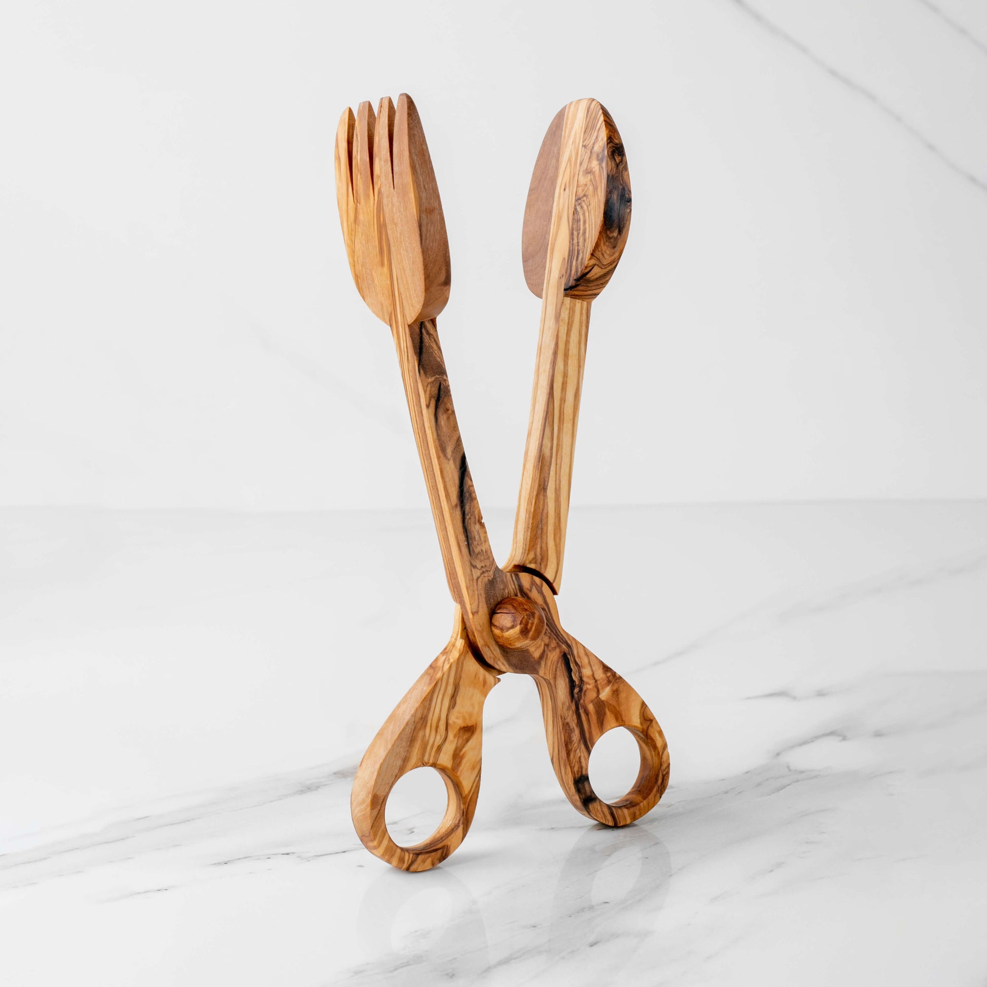 Elegant handmade olive wood salad tongs with fork and spoon ends, eco-friendly serving utensils on a marble surface.