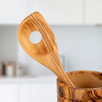Handmade olive wood ladle resting in a polished wooden holder, showcasing its durable craftsmanship and unique design.